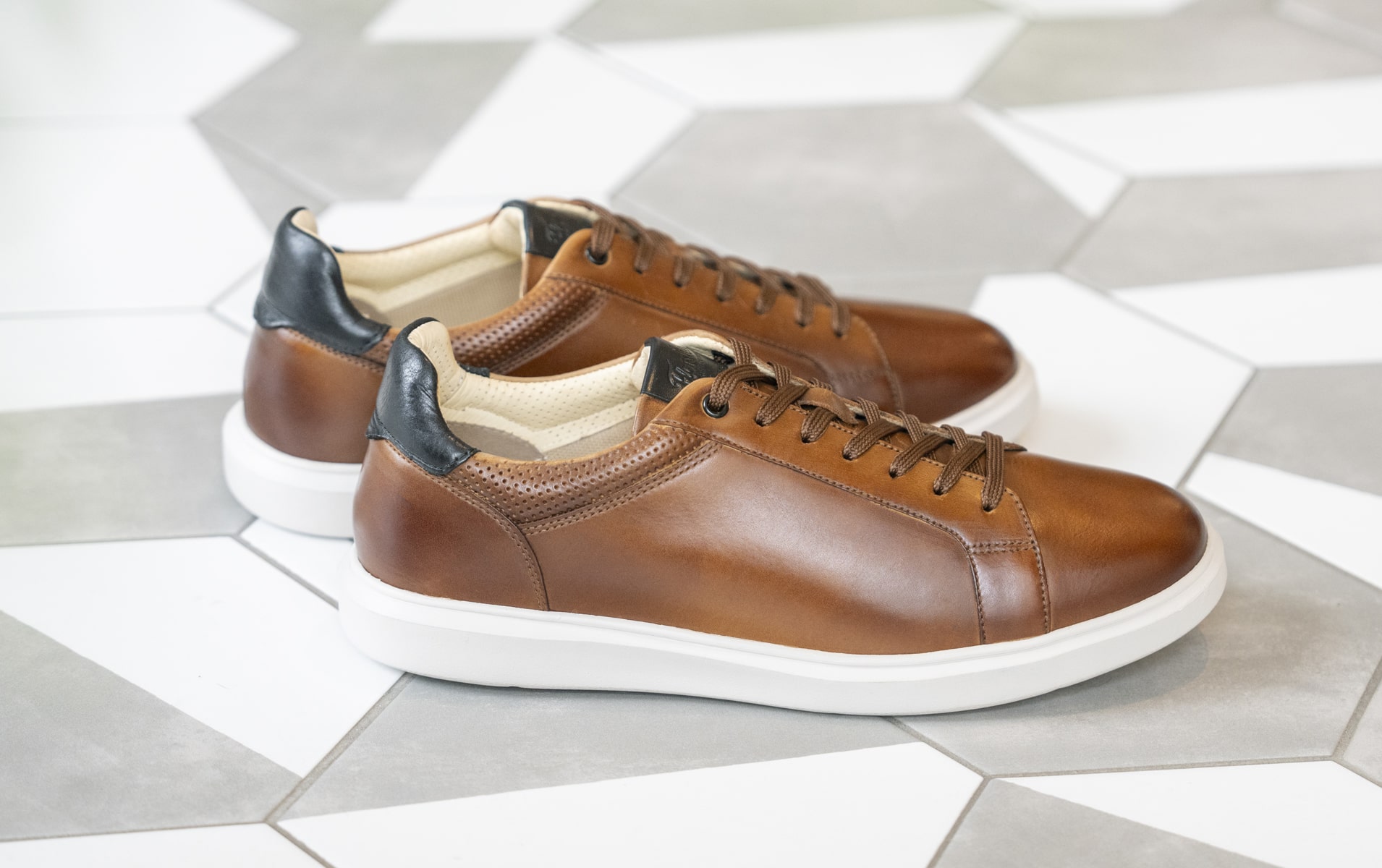 Image features the Social sneaker in cognac on a tile floor.